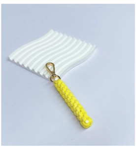 Detail showing a handmade yellow braided rope keychain with a golden spring clip hook