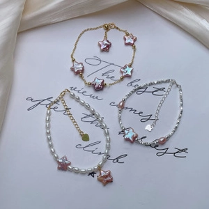 Tre eleganti bracciali di perle d'acqua dolce con ciondoli a stella rosa su sfondo di seta