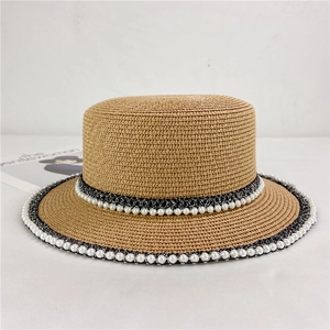 Detail of vintage straw boater hat featuring pearl embellishments and lace woven bands