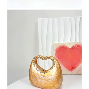Detail of acrylic heart clutch bag featuring marble texture and rhinestone handle