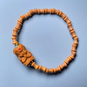 Close-up of sandalwood bamboo-style beads and a carved Buddha head pendant