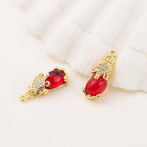 Close-up of gold-plated metal fox pendants with red gemstone and sparkling rhinestones