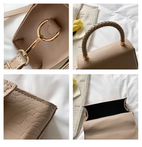 Detail view of beige crocodile embossed leather with gold hardware and woven handle