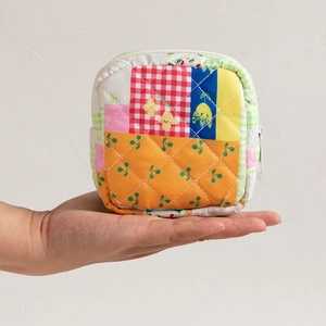 Close-up of quilted floral patchwork pouch held by hand showing textured fabric details