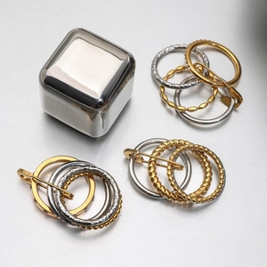 Close-up of luxury gold and silver textured metal rings on a brushed metallic background