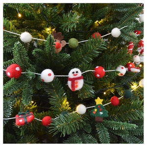 Detail of wool felt Christmas ornaments with reindeer and tree on a festive pine branch