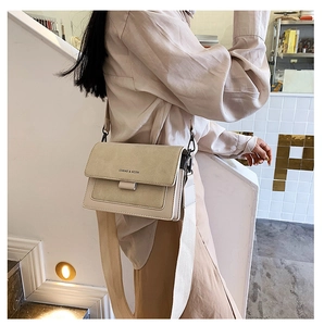 Fashionable beige crossbody square bag with wide strap shown on a model side view