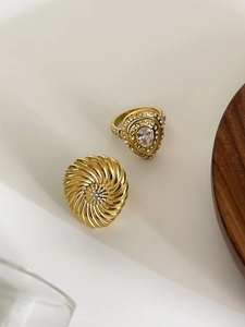 Detailed view of two gold layered rings featuring twisted diamond and teardrop stone settings