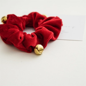 Close-up of red velvet scrunchie with golden bells for Christmas hair styling