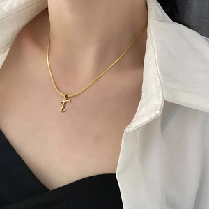 Close-up view of gold titanium steel flat snake chain with letter T pendant on model