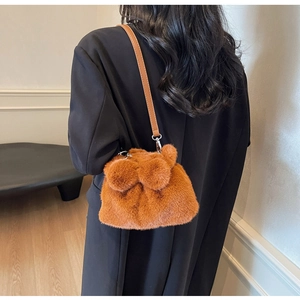 Detail of caramel plush bucket bag with leather strap shown on shoulder
