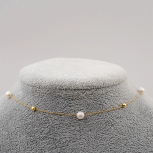 Minimalist freshwater pearl gold choker necklace displayed on a grey velvet bust model