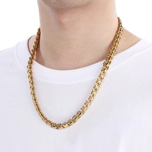Close-up of a gold chunky curb link chain necklace worn by a model in a white t-shirt