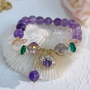 Macro shot of purple amethyst beads and gold flower pendant with micro-set zircon