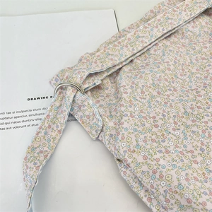 Detailed close-up of floral canvas bag with metal D-ring buckle and fabric strap