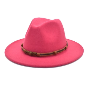 Detail of rose red wool fedora hat featuring a vintage bronze skull on a brown leather band