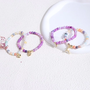 Detail of colorful freshwater pearl bracelets with gold heart and deer charms on white background