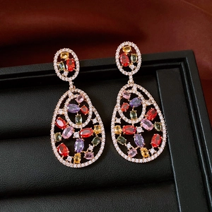 Macro detail of teardrop earrings with colorful zircon stones on a black jewelry tray