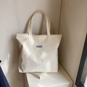 Close-up of cream corduroy tote bag texture with Fashion Instinct logo label