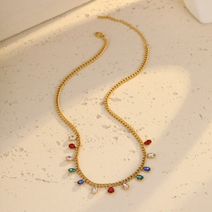 Detail of gold necklace with twelve colorful teardrop crystal pendants on a textured surface