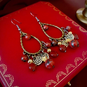 Gros plan détaillé de boucles d'oreilles ethniques avec perles de marbre rouge et bronze