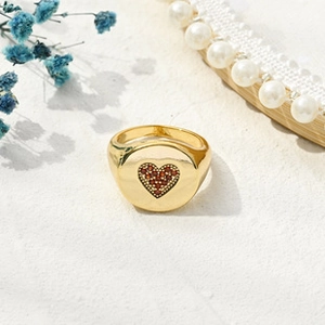 Detail of gold dome ring featuring a small red rhinestone heart on flat round top surface