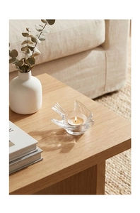 Macro shot of bird-shaped glass candle holder with a tea light on a wooden table