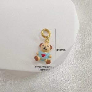 Detail view of 20.8mm gold teddy bear charm with blue enamel and red heart accent