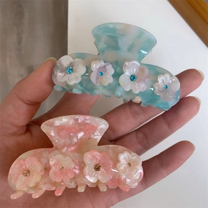 Floral acetate hair claws in blue and pink mica patterns with sparkling rhinestone center