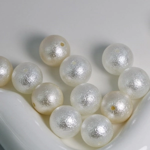 Close-up of cream white wrinkled ABS imitation pearls with smooth matte texture and holes