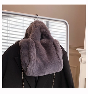 Vue détaillée du sac cabas en peluche grise avec chaîne en métal sur un blazer noir