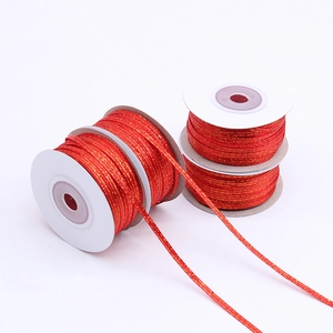 Close-up of red and gold metallic braided cord on white spools for DIY gift wrapping