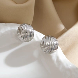 Elegant textured silver ball stud earrings displayed on a white tray with silk fabric