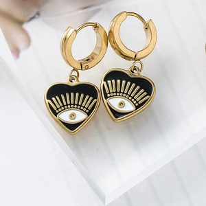 Detailed close-up of heart-shaped evil eye dangle earrings with gold finish and enamel inlay