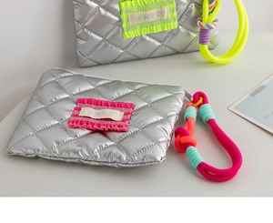 Detail of silver quilted waterproof PU cosmetic bag with vibrant ruffled logo handles
