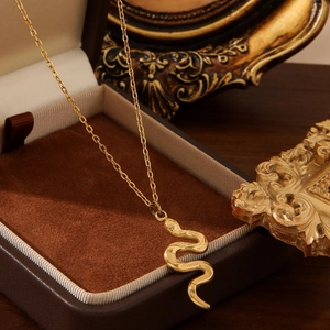 Vintage gold snake pendant necklace in titanium steel on a dark velvet jewelry box