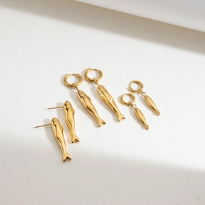 Detailed view of three pairs of golden fish-shaped earrings with hoop and stud designs