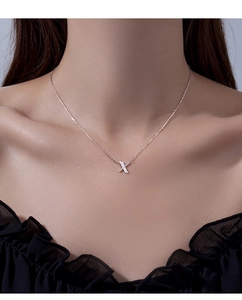 Close-up of S925 silver letter X necklace pendant with sparkling zirconia on model