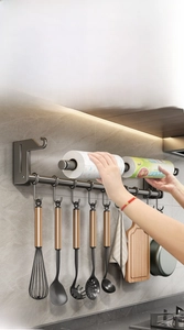 Detail of grey kitchen wall rack with hooks holding a spatula, whisk and paper towels