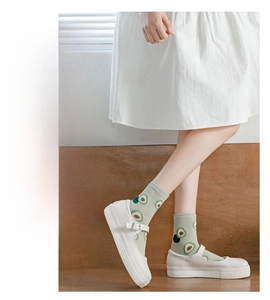 Detail of green mid-calf cotton socks with cute avocado patterns and white Mary Janes
