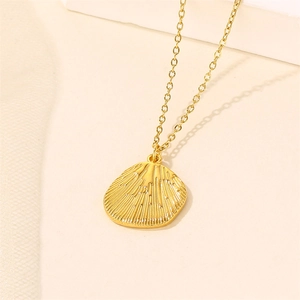 Minimalist gold shell pendant necklace on a textured beige surface for women