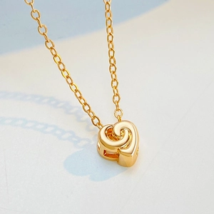 Gros plan d'un pendentif cœur doré avec texture en spirale 3D et chaîne raffinée