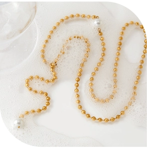 Detail of a gold-plated Y-shaped beaded necklace featuring two elegant white pearls