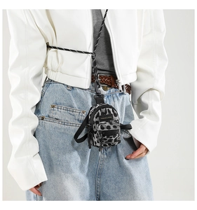 Close-up of mini leopard print crossbody bag with fashion label on white jacket