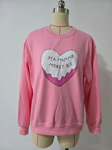 Détail d'un sweat oversize rose avec un cœur blanc et une impression de texte russe
