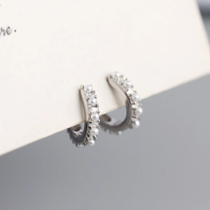 Close-up of S925 sterling silver hoop earrings with embedded white pearls on card