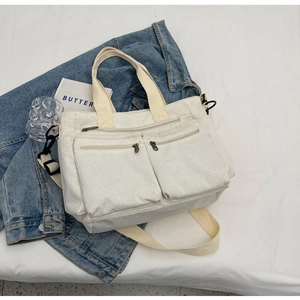 White corduroy tote bag with dual front zipper pockets and adjustable shoulder strap