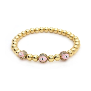 Detailed macro view of 18K gold-plated beaded bracelet with pink evil eye enamel charms