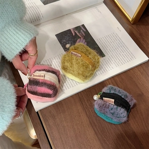 Detailed close-up of plush wool protective cases for AirPods with pearl charms and zippers