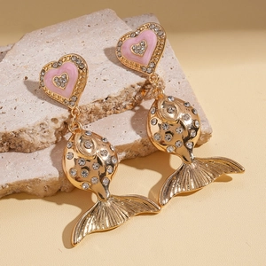 Close-up of heart-shaped pink enamel stud and fish pendant earring with rhinestones